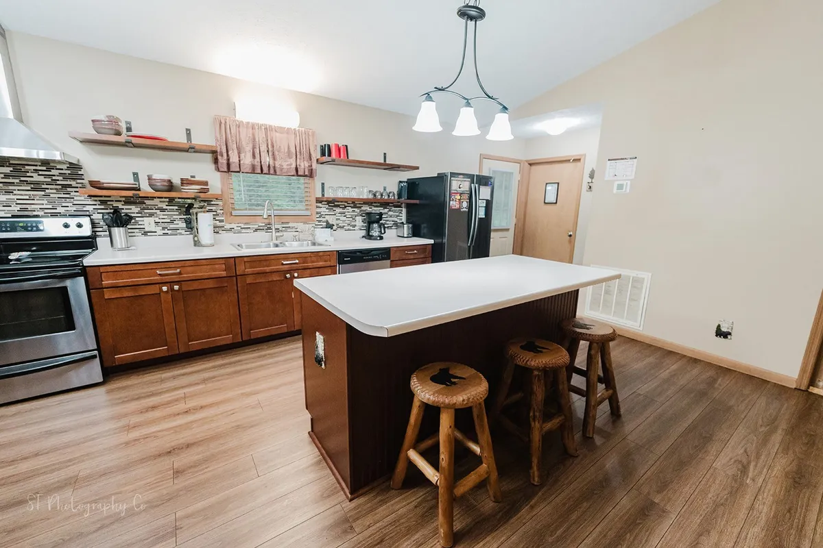 A bright and welcoming kitchen with a spacious island, stools, modern appliances, and open shelving—perfect for intimate dinners, festive cooking sessions, or casual breakfasts with family and friends.