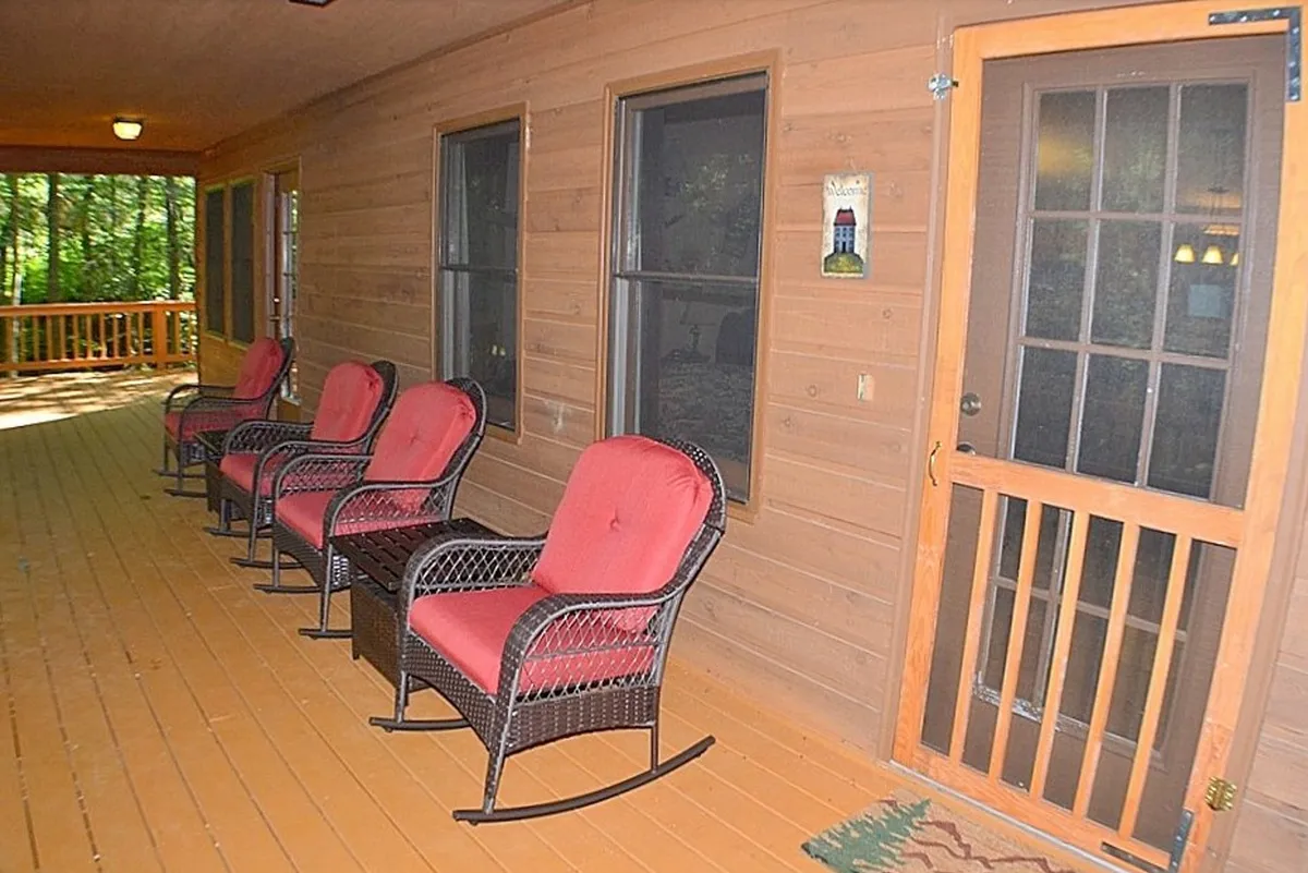 A charming porch area with comfortable rocking chairs, wooden details, and views out to the tree-lined surroundings. The space feels calm and welcoming, offering a shaded retreat to relax, read, or simply watch the world go by, with plenty of room for pets to rest nearby.
