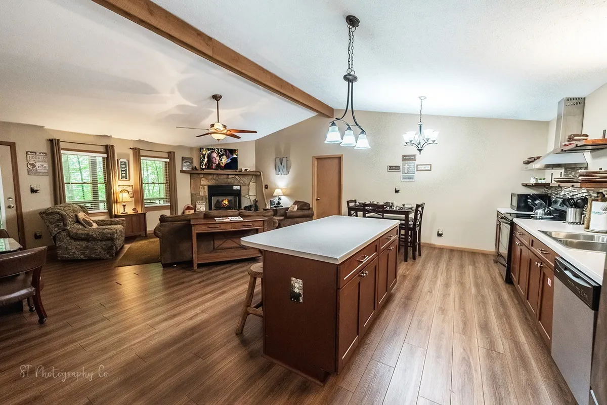 A warm, inviting interior featuring an island counter, comfortable seating area, fireplace, and window views of the outdoors. This space is suited for family dinners, game nights, or relaxing after a day of outdoor activities with pets nearby.