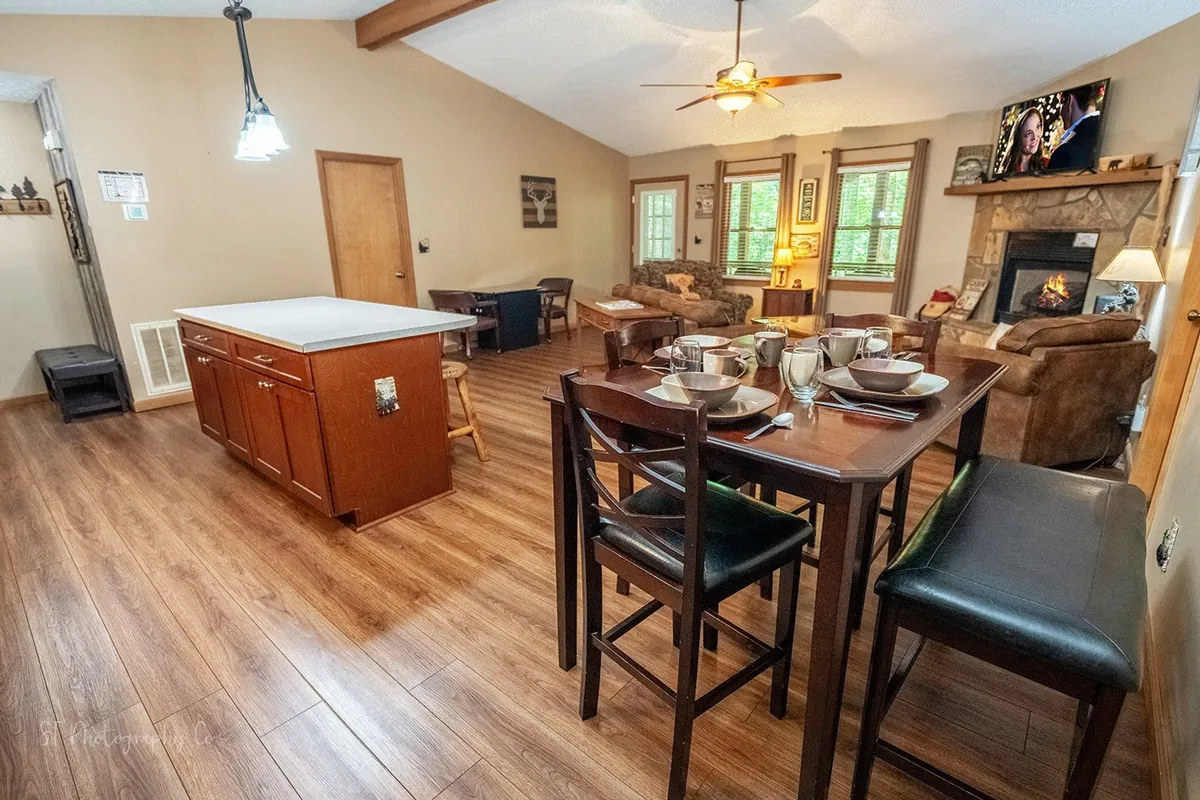 This image features a dining table set for a meal, a kitchen island, and a cozy fireplace, all within a spacious, open-plan area. The inviting setup suggests a space designed for family meals, casual gatherings, and relaxing by the fire, which directly aligns with the section's emphasis on shared experiences and togetherness.