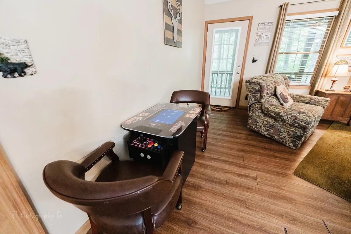 A spacious living area with a game table, comfortable armchairs, a couch, and large window, inviting guests to play games, socialize, or relax. The decor is warm and welcoming, designed for group activities and cozy conversations.